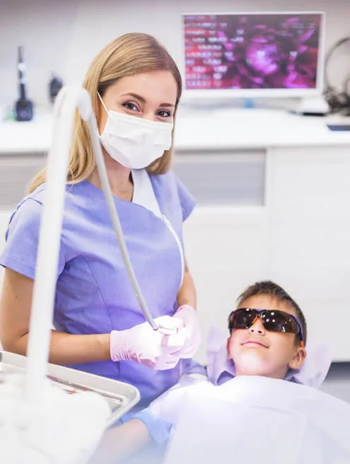 Dental hygienist with young patient at dental office